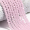 Pink faceted crystal glass beads strung together on a white surface.