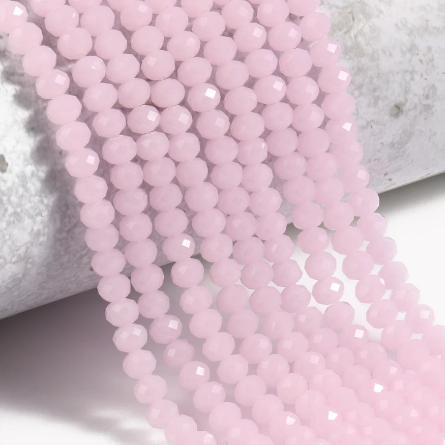 Pink faceted crystal glass beads strung together on a white surface.