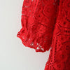 A close-up of a red lace princess dress with a doll collar, showing the intricate fabric detail.