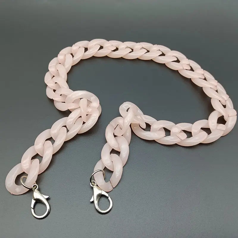 A flexible pink acrylic bag chain strap with metal clips is displayed against a gray background.