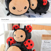 A black and orange plush toy of a bee with ladybug spots sitting on a piece of paper.