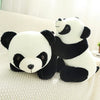 A white and black panda plush toy lying on a light-colored fabric surface.