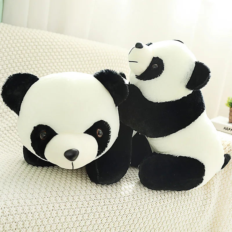 A white and black panda plush toy lying on a light-colored fabric surface.