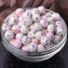 A bowl filled with small, round floral ceramic beads in shades of pink and white.