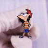 A hand wearing a white glove holds an enamel pin of the cartoon character Phineas.