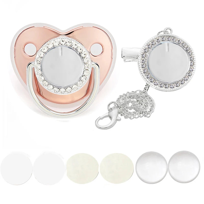 A pink and silver baby pacifier clip set featuring a heart-shaped body and rhinestone accents.