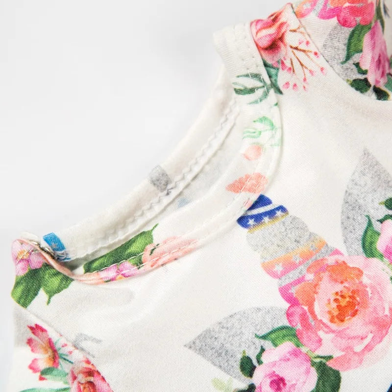 Close-up of a handmade doll dress featuring a floral print with pink and green roses on a white background.