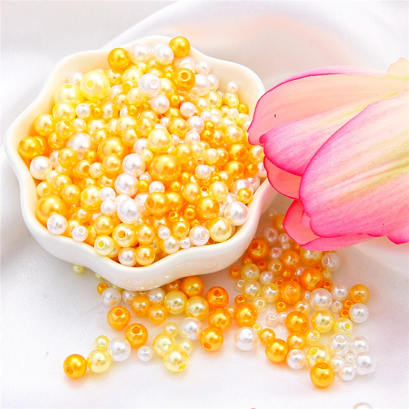 A small white dish filled with assorted yellow and white pearl beads, some spilled onto the surface.