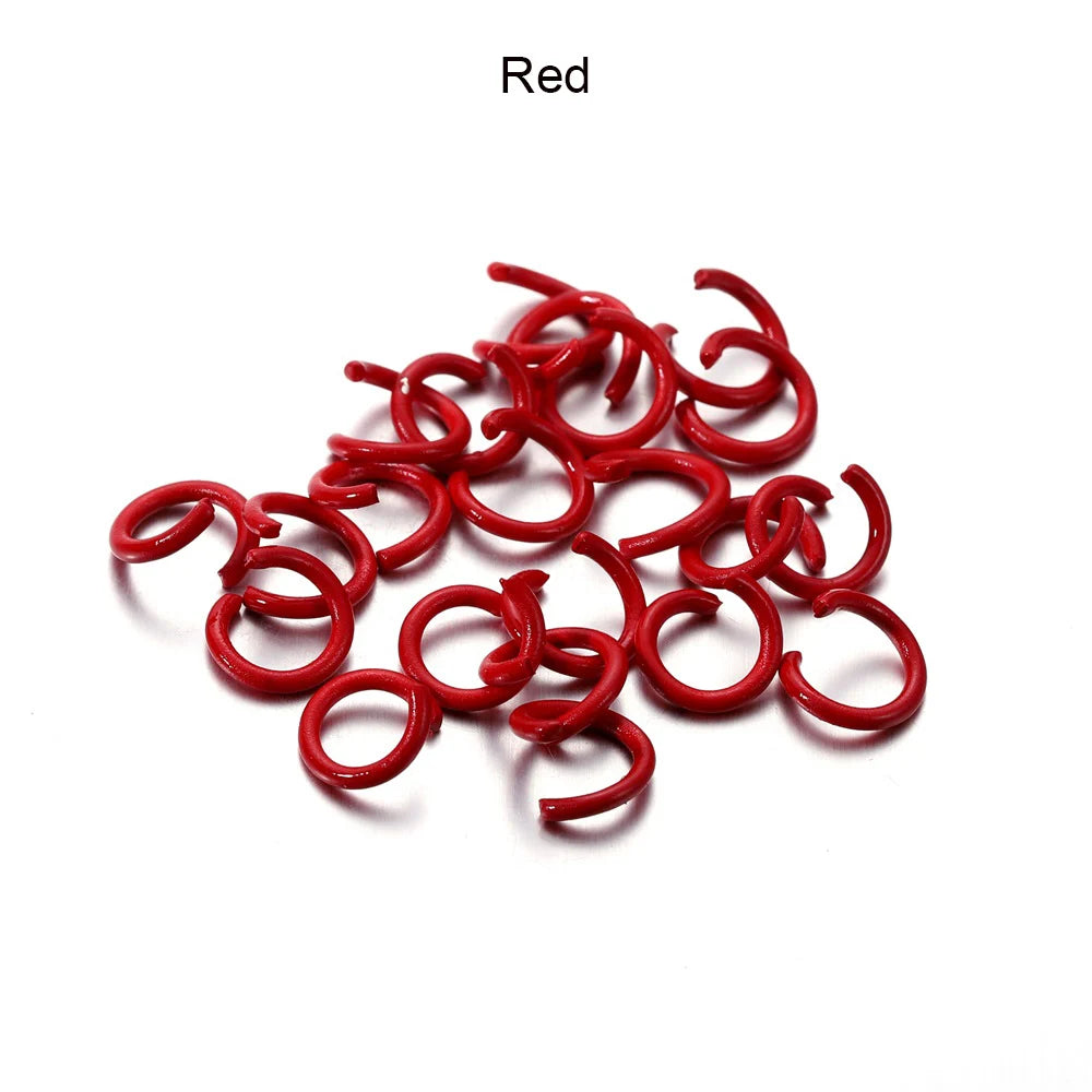 A pile of red metal open jump rings for DIY jewelry making.