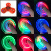 A series of images showing a glow-in-the-dark LED fidget spinner rotating and emitting various colors like blue, green, and r