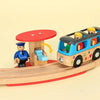 A wooden train track set featuring airport and gas station scenes with minifigure passengers.