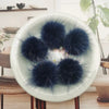 A collection of dark blue and black mink fur pom poms displayed on a white plate.