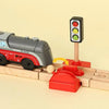 A model train set featuring a gray and red locomotive, a traffic light, and track pieces.