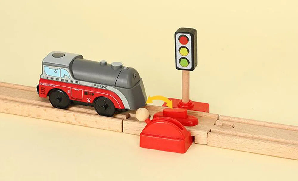 A model train set featuring a gray and red locomotive, a traffic light, and track pieces.