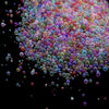 A close-up view of a pile of multi-colored mini glass bubble beads scattered on a dark surface.