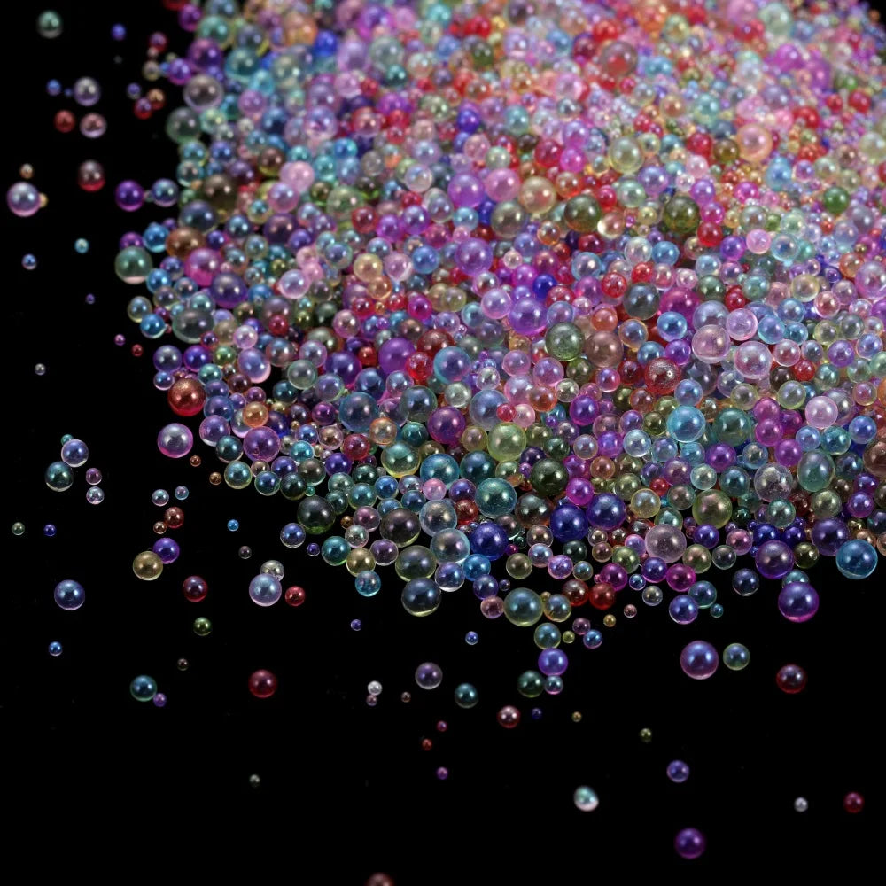 A close-up view of a pile of multi-colored mini glass bubble beads scattered on a dark surface.