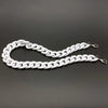 A silver-toned acrylic bag chain strap with links and clips laid out on a dark gray surface.