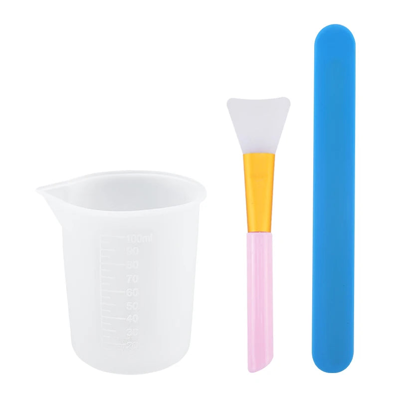 A set of reusable silicone resin mixing tools including a measuring cup and stir sticks in white, yellow, and blue.