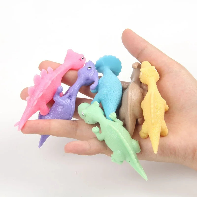 A hand holds several brightly colored, stretchy rubber chicken slingshot fidget toys.
