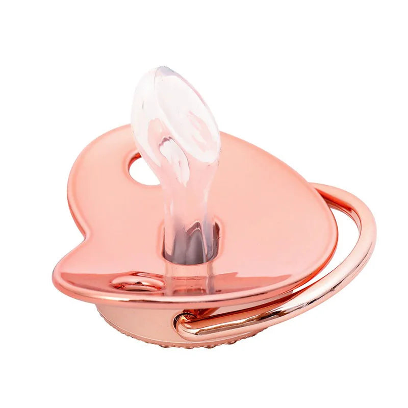 A rose gold crystal bling pacifier for newborns with a heart-shaped silicone shield and a handle.