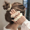 A close-up of a woman's hair styled in an updo adorned with elegant pearl hair ties and bow scrunchies.