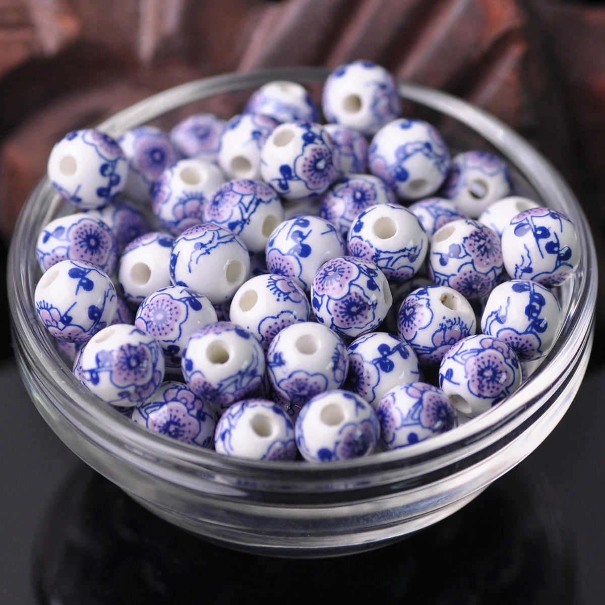 A glass bowl filled with small white and purple floral ceramic beads for jewelry making