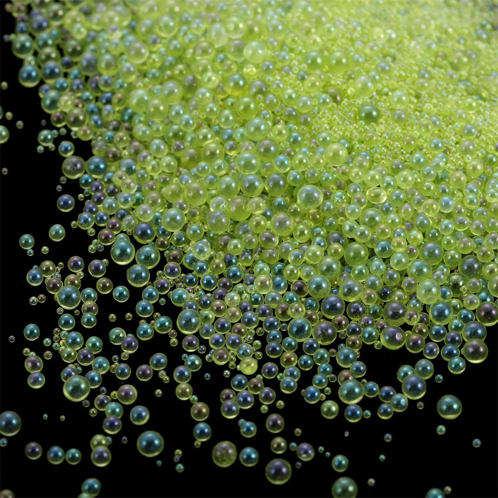 A close-up view of small, translucent green glass bubble beads scattered against a black background.