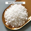 A pile of white beeswax pellets in a gold-colored dish.