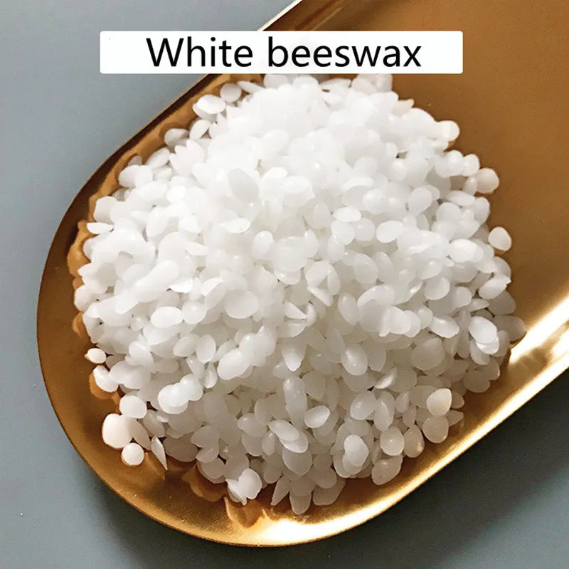 A pile of white beeswax pellets in a gold-colored dish.