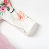 Close-up of a white long-sleeved garment with pink floral embroidery
