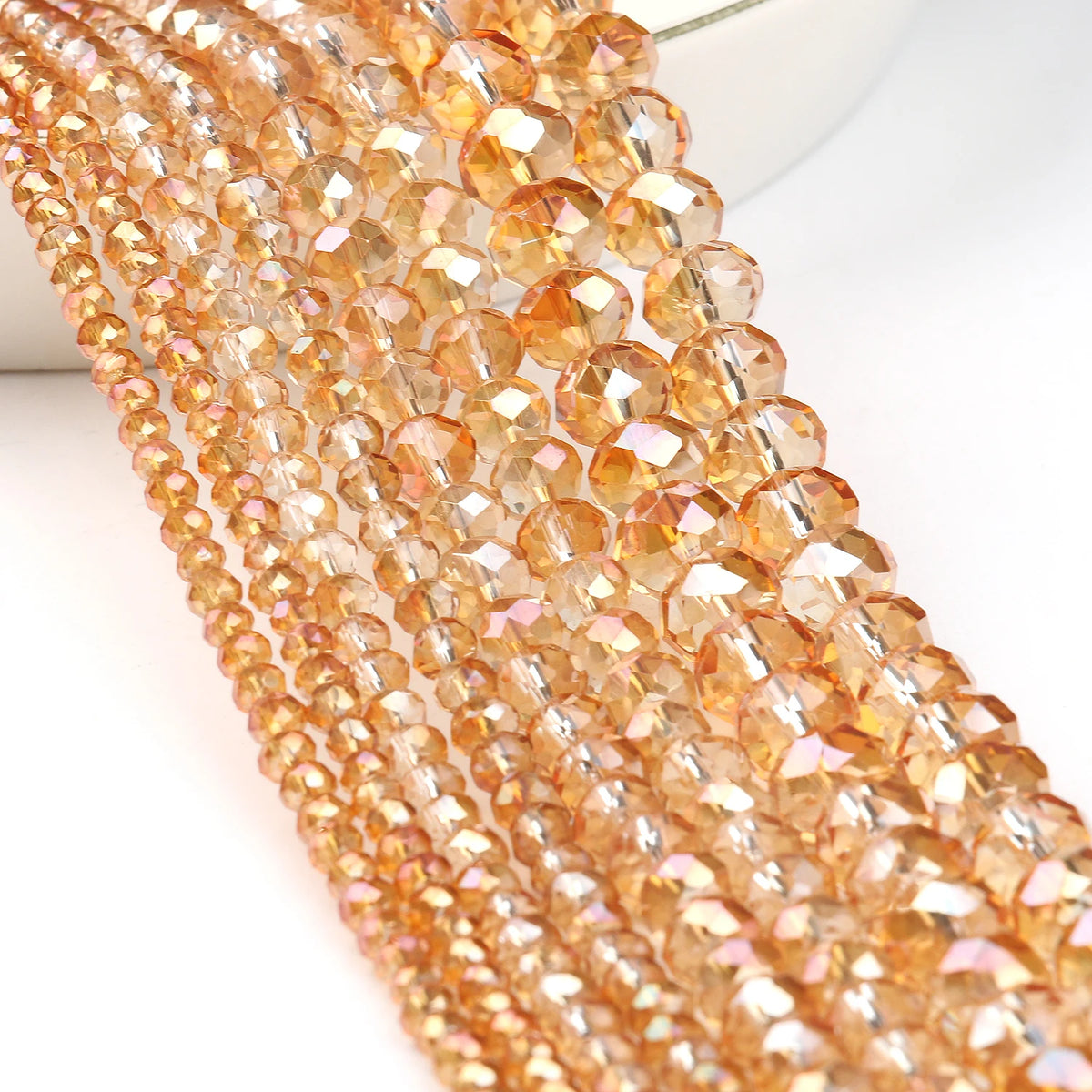 A close-up of multiple strands of faceted amber crystal glass beads for jewelry making