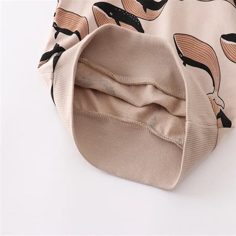 A beige long sleeve pullover sweatshirt with a black whale print visible inside the sleeve cuff.