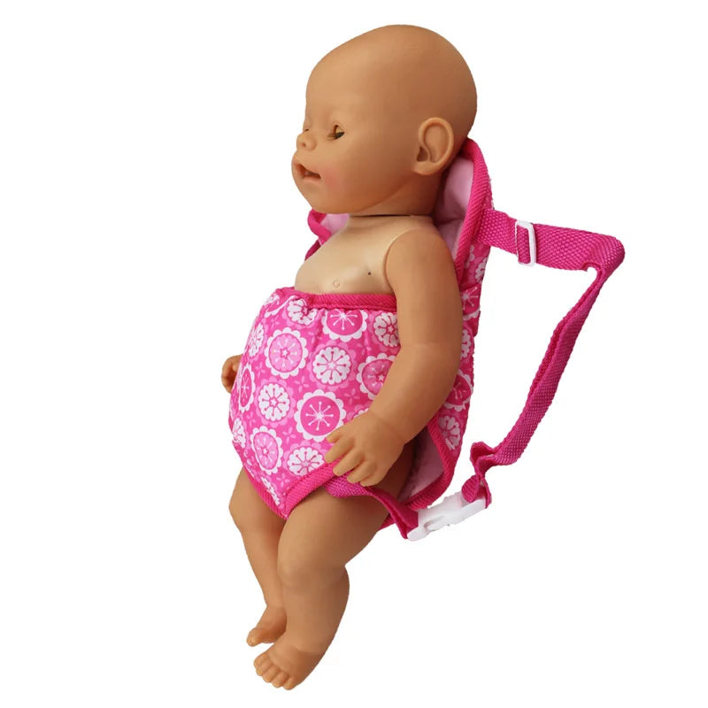 A baby doll wearing a pink patterned mini backpack.