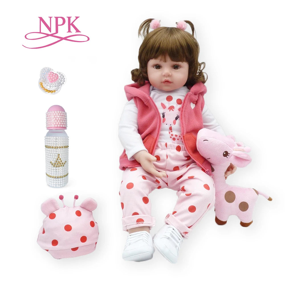 A baby doll wearing a pink outfit with a pink jacket and pink accessories, next to various small decorative items.