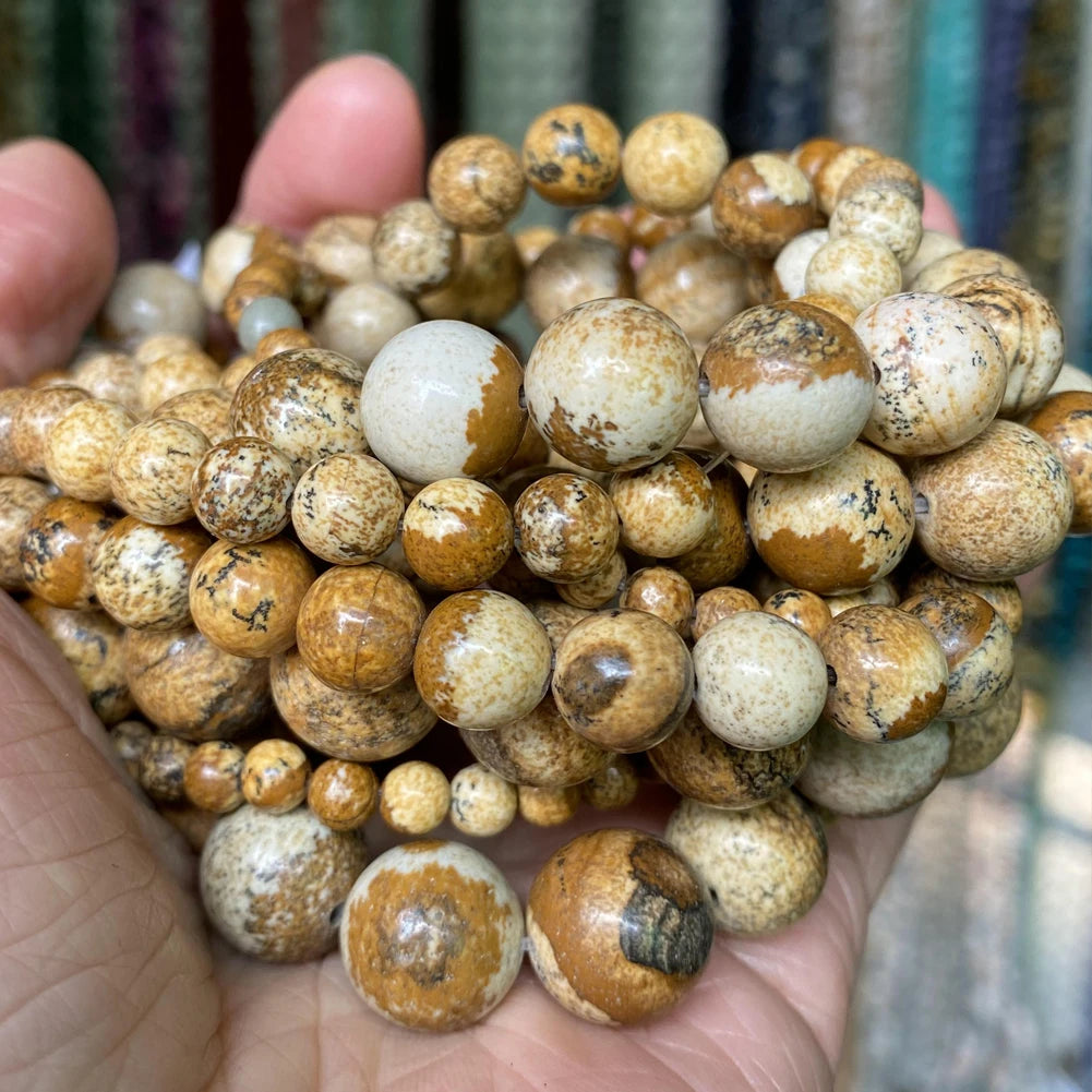 A handful of natural gemstone beads in various shades of brown and tan, including tiger eye and lava stones.