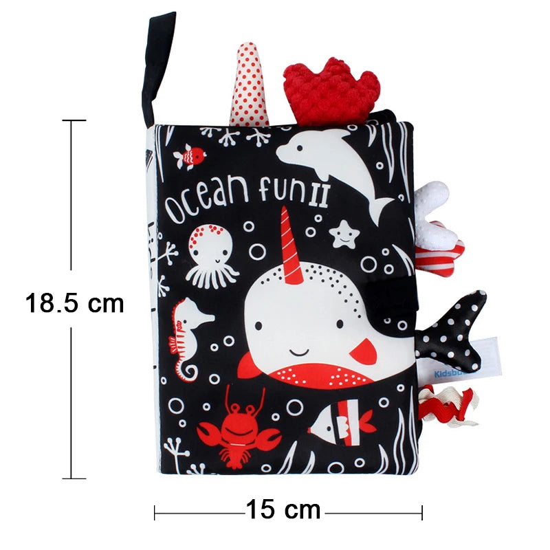 A black cloth book featuring various sea animals like a whale, octopus, and a unicorn in red and white.