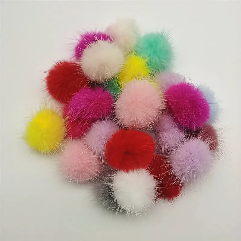 A collection of colorful, fluffy mink fur pom poms in shades of pink, red, yellow, and white.