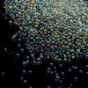 A close-up view of tiny, iridescent glass bubble beads scattered against a dark background.