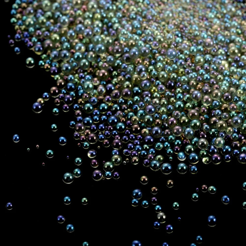 A close-up view of tiny, iridescent glass bubble beads scattered against a dark background.