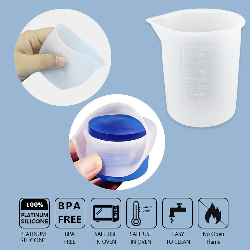 A set of reusable silicone resin mixing tools including a measuring cup and stir sticks shown next to a clear measuring cup.