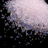 A pile of iridescent pink and purple glass bubble beads scattered against a black background.