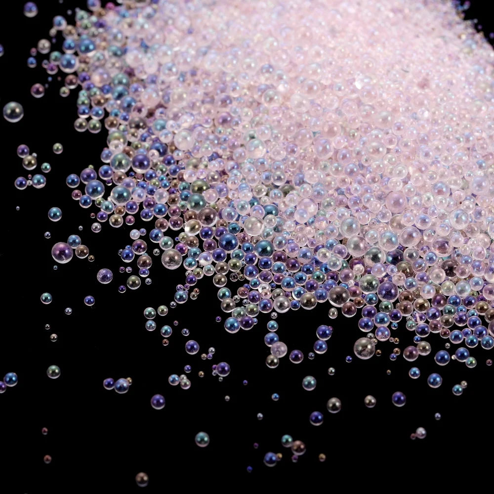 A pile of iridescent pink and purple glass bubble beads scattered against a black background.