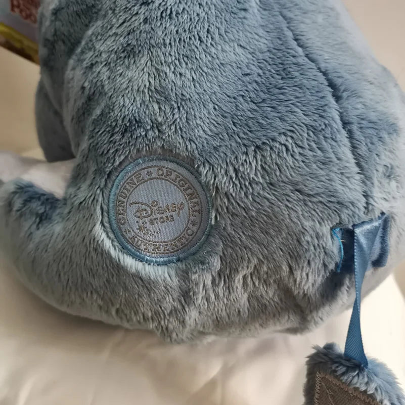 A close-up of a soft blue Eeyore plush toy with light gray fur and a circular Disney tag on its back.