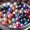 A close-up shot of various colorful imitation pearl beads in a glass bowl for DIY jewelry making