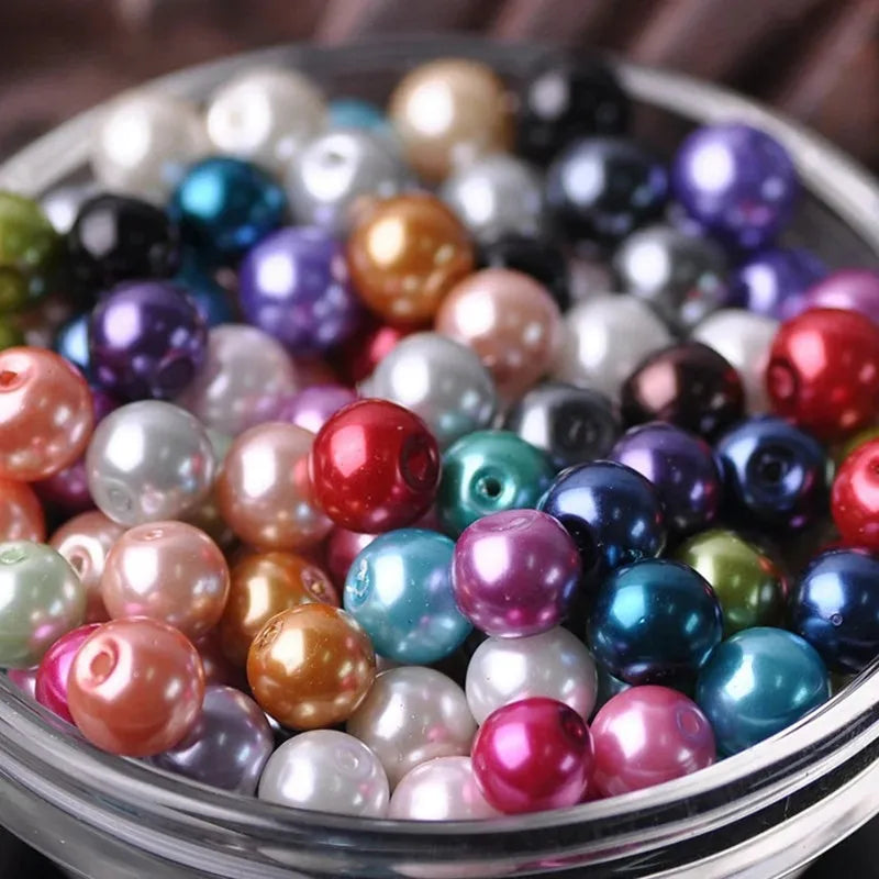 A close-up shot of various colorful imitation pearl beads in a glass bowl for DIY jewelry making