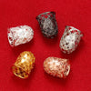 A collection of four ornate bead and tassel caps for jewelry making displayed on a red fabric background.