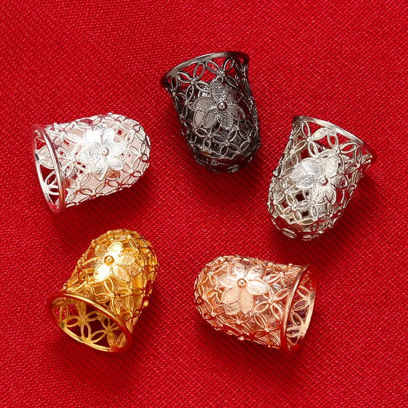 A collection of four ornate bead and tassel caps for jewelry making displayed on a red fabric background.