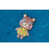 A brown bear figure made of LEGO bricks with an orange and green patterned shirt set against a blue background.