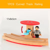 A single piece of curved wooden track railing used for train models, shown with a miniature figure and a red base.