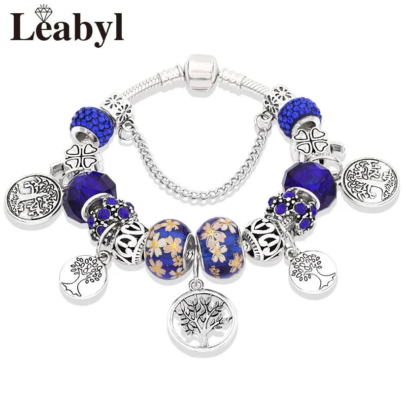Silver bracelet featuring blue and gold floral accents with Tree of Life crystal charms